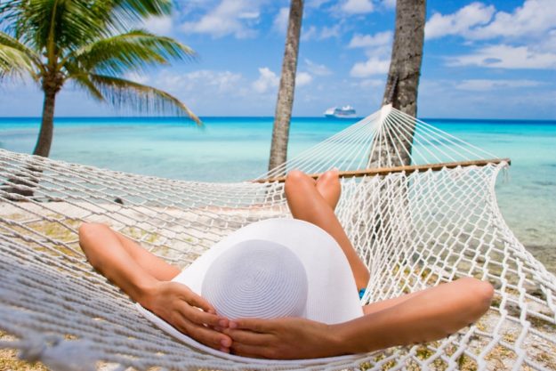 Woman relaxing on hammock with white hat